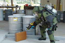 Bomb suit person checking suitcase for explosives