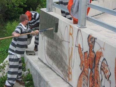 Inmate painting over graffiti