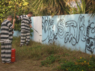 2 inmates painting over graffiti